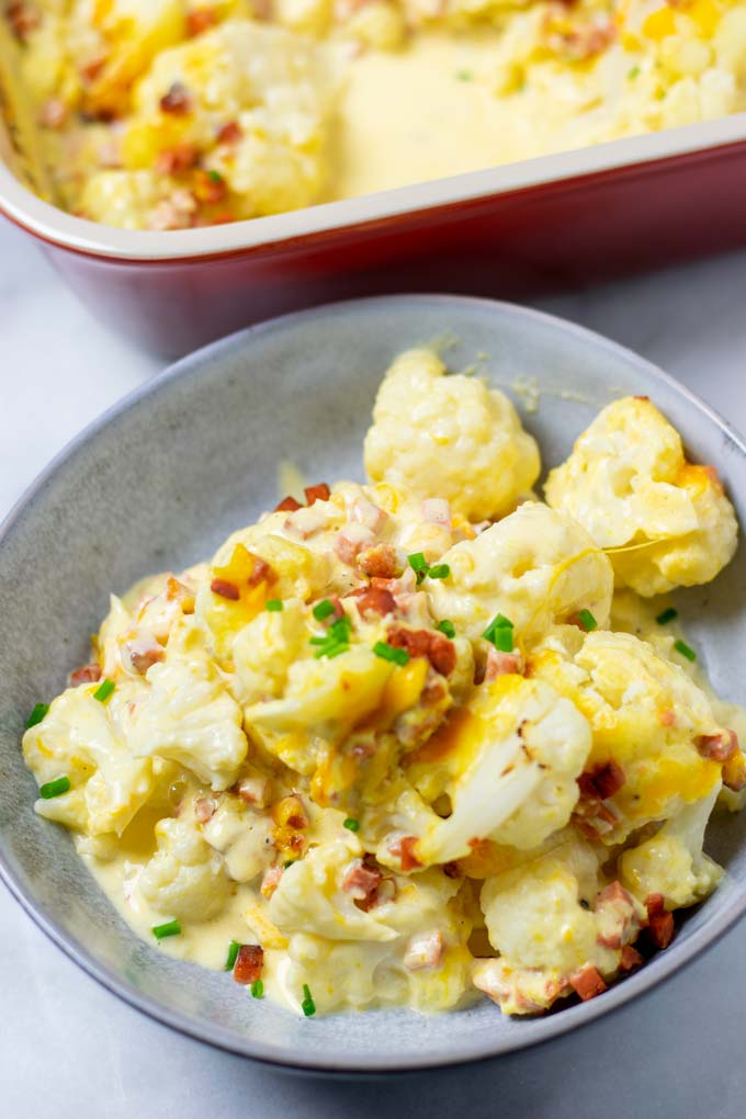 A large portion of the Cauliflower Bake on a plate with the casserole dish visible in the background.