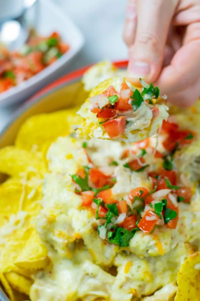 Closeup on a taco being lifted from the dish, garnished with tomato topping.