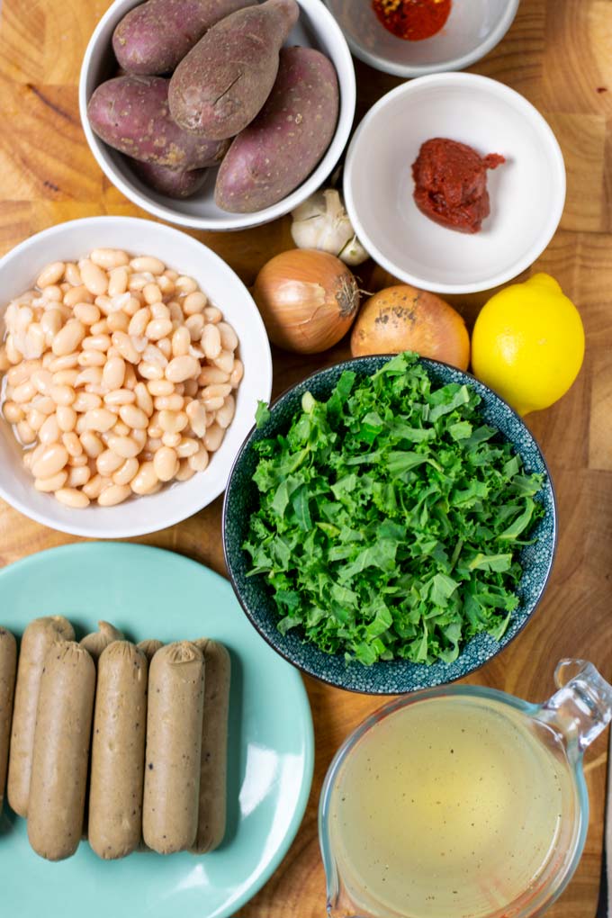 Ingredients needed to make the Kale Soup are collected in bowls on a wooden board.