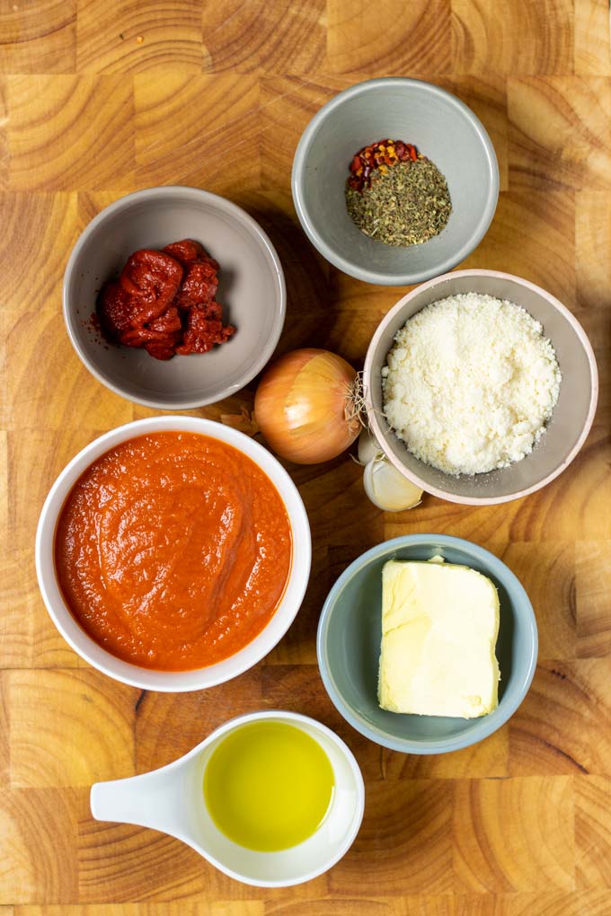 Ingredients needed for making this Pomodoro Sauce are assembled on a wooden board.
