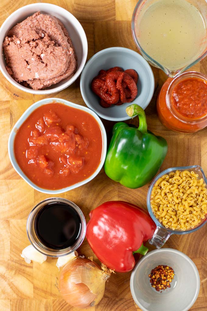Ingredients needed to make American Goulash are assembled on a wooden board.