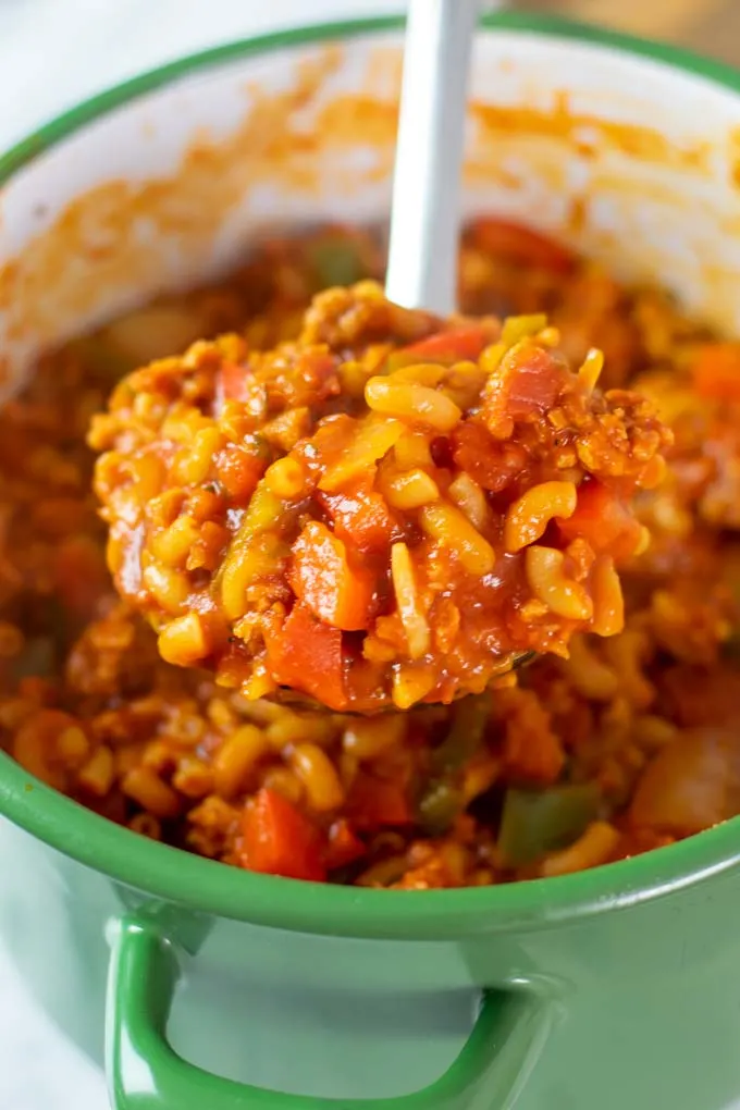 A large spoon of the American Goulash is lifted from the pot.