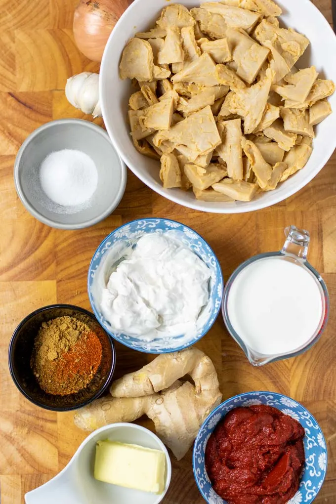 Ingredients needed to make this vegan Butter Chicken are assembled on a wooden board.