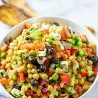 Side view of the Chickpea Salad in a serving bowl with wooden salad cutlery in the background.