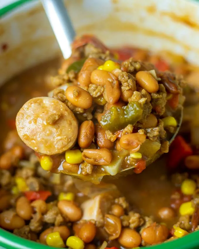 A large spoon lifts a portion of the Cowboy Stew from the pot.