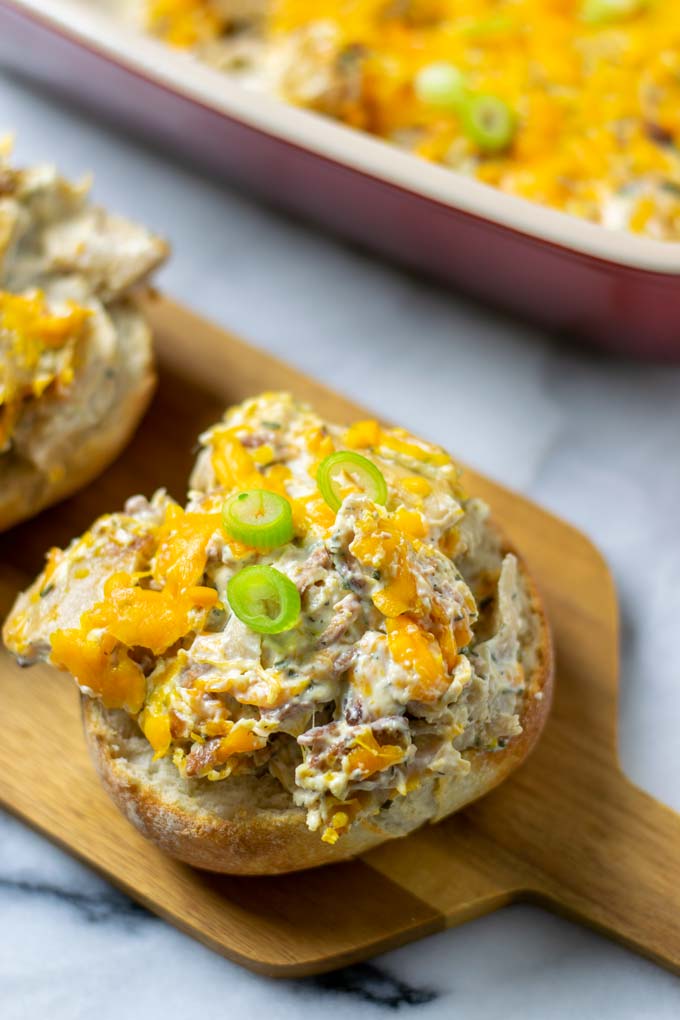 Crack Chicken is served on the bottom of a bun. The casserole dish is visible in the background.