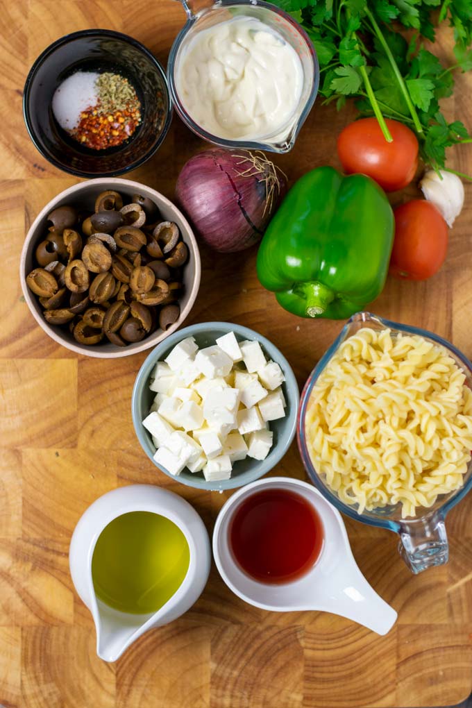 Ingredients needed to make the Easy Pasta Salad are assembled on a wooden board.