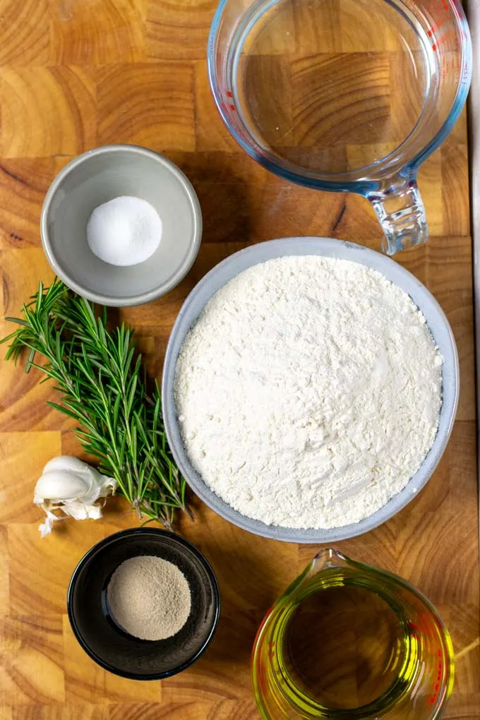 Ingredients needed to make the Focaccia are assembled on a wooden board.