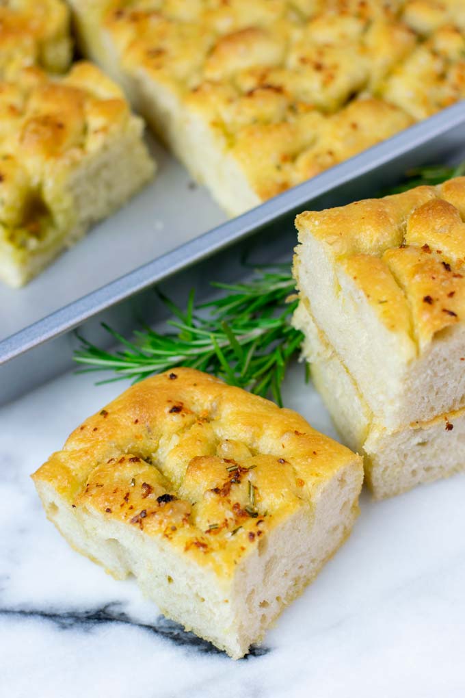 Pieces of Focaccia are stacked with the baking pan in the background.