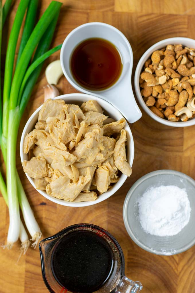 Ingredients needed to make the Cashew Chicken are assembled on a wooden board.