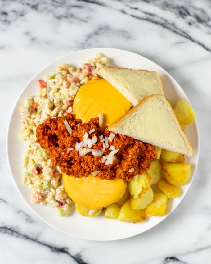 Showing how to finish the Garbage Plate with diced onions and some bread.