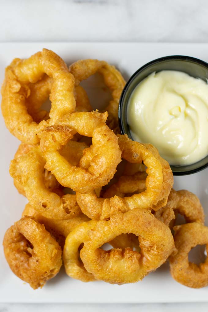 Top view of a large plate with Onion Rings and a portion of vegan mayo.