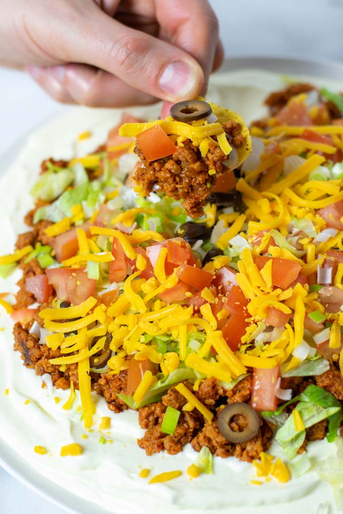 A taco chip is dipped into the Taco Dip.