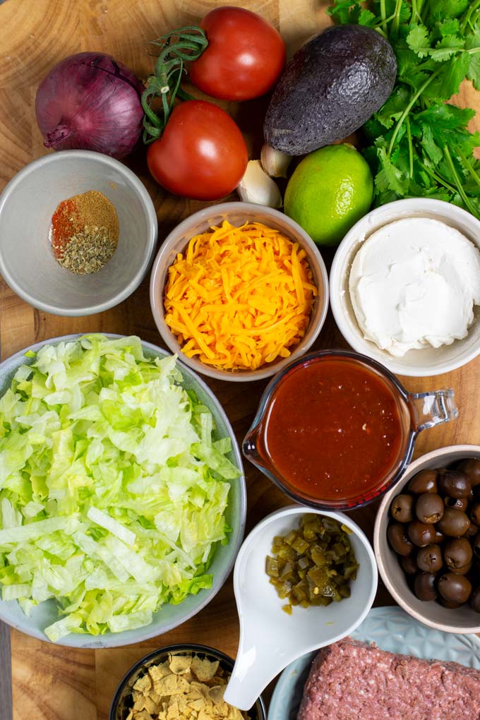 Ingredients needed to make the Taco Salad are assembled on a wooden board.