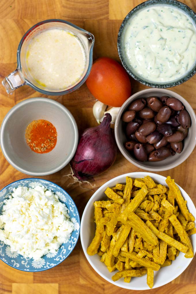 Ingredients for making Chicken Gyro are assembled on a wooden board.