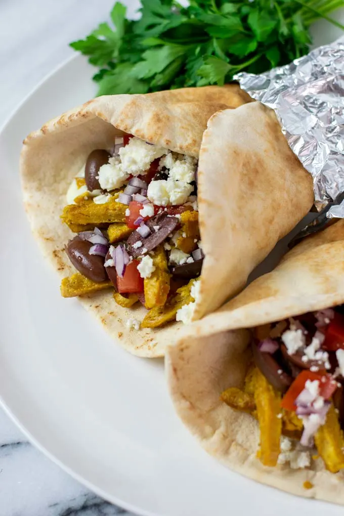 Two Chicken Gyros are rolled and served on a plate.