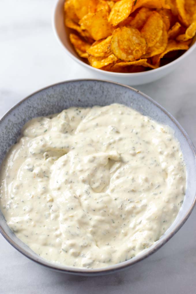 The Creamy Jalapeño Sauce in a bowl with some chips in the background.