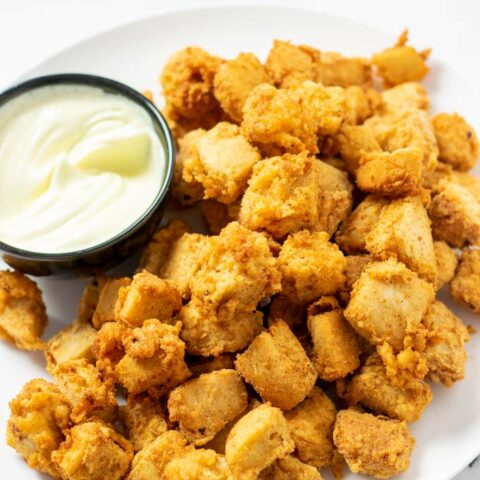 A large plate of of the Popcorn Chicken with a small bowl of mayonnaise.