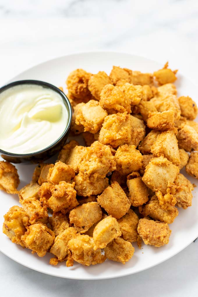 A large plate of of the Popcorn Chicken with a small bowl of mayonnaise.