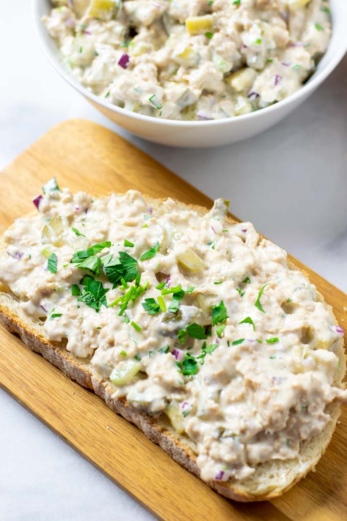 A slice of Tuna sandwich in the foreground, with a serving bowl in the background.