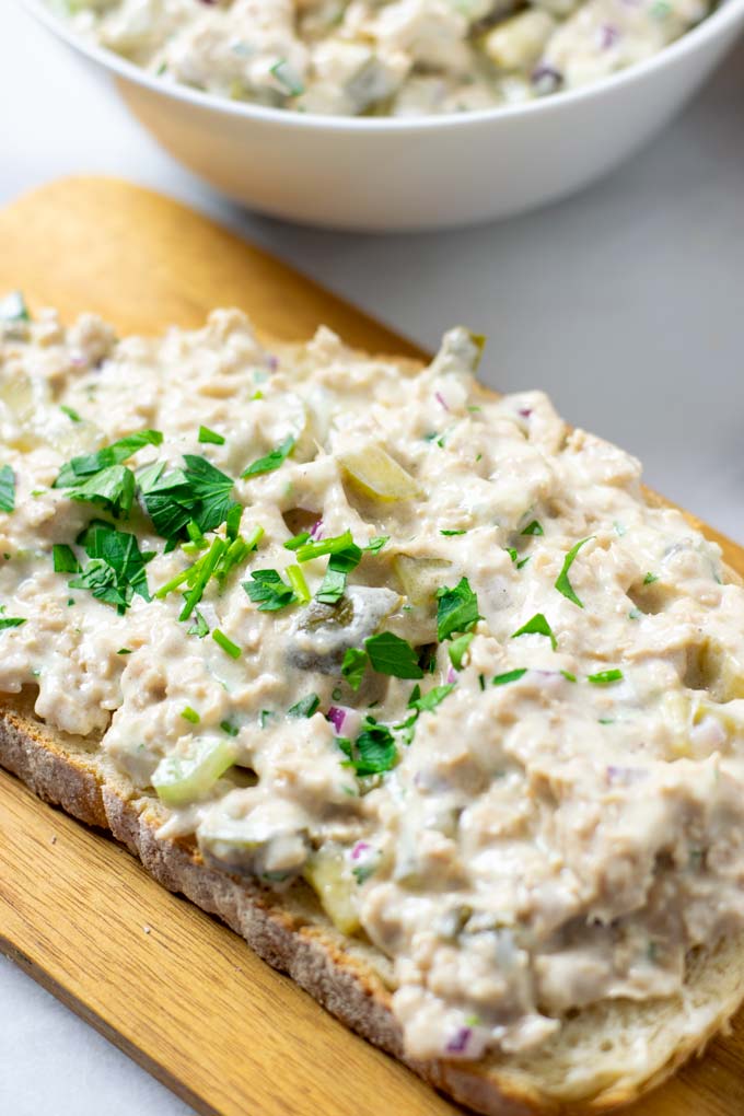 Closeup of a slice of bread with the Tuna Salad and garnished with fresh herbs.