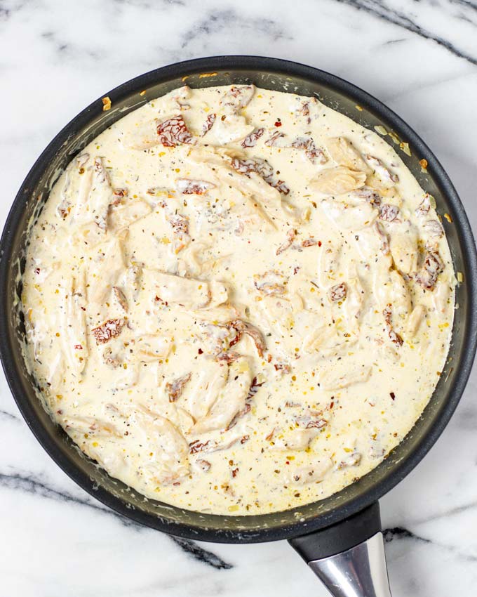 Creamy sauce with sun dried tomatoes in a pan.