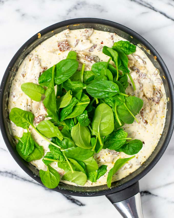 Fresh spinach is added to the pan with the creamy sauce.