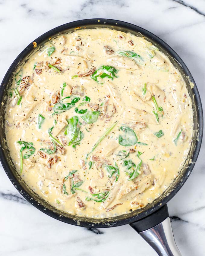 Top view on the pan with the creamy sauce with sun dried tomatoes and spinach.