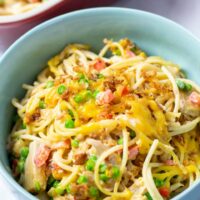 A portion of the Chicken Spaghetti is served in a bowl, the casserole dish is visible in the background.