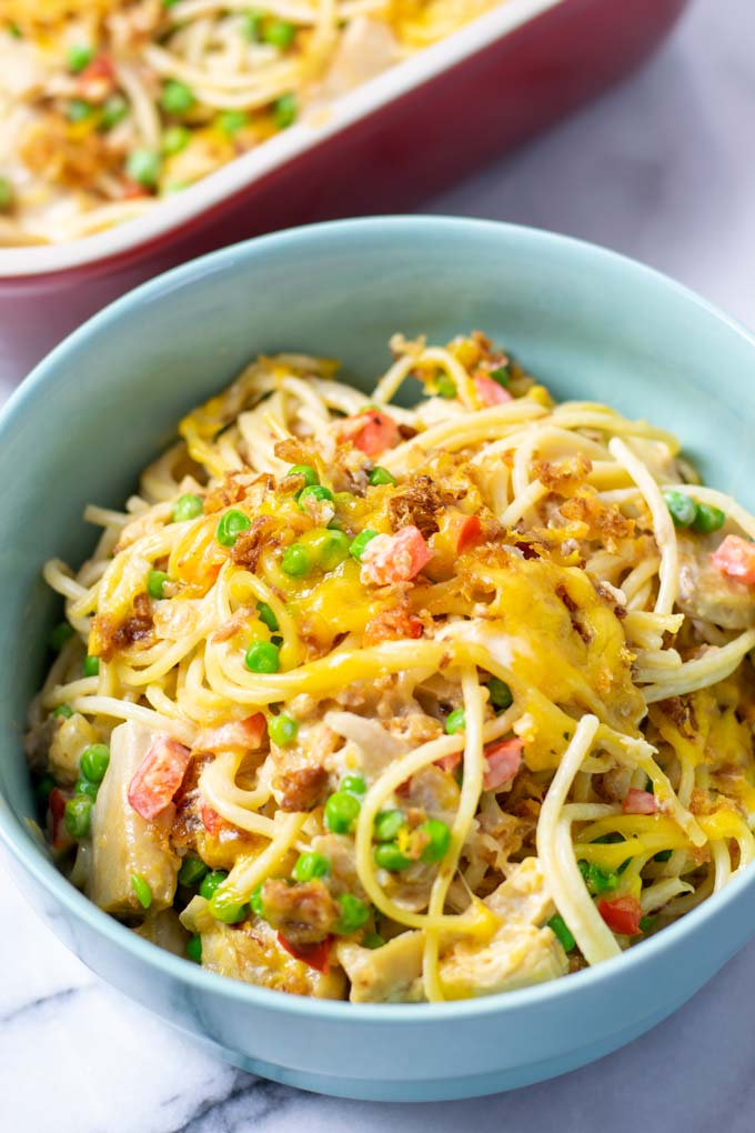 A portion of the Chicken Spaghetti is served in a bowl, the casserole dish is visible in the background.