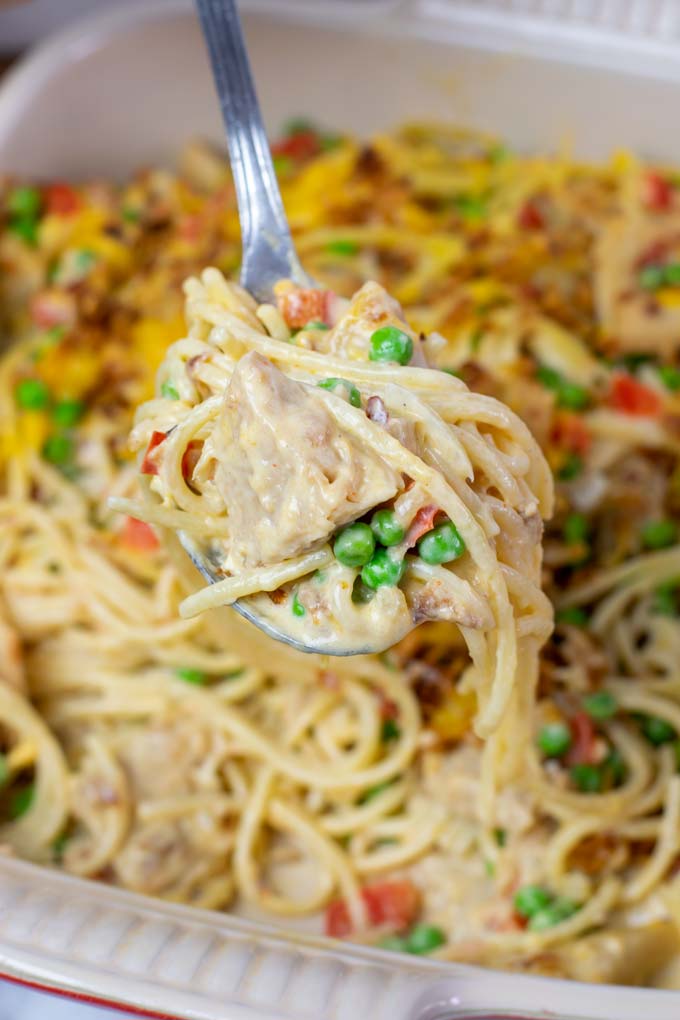 Closeup of a large serving spoon full of the Chicken Spaghetti, with the vegan chicken, peas, bell pepper and creamy sauce clearly visible.