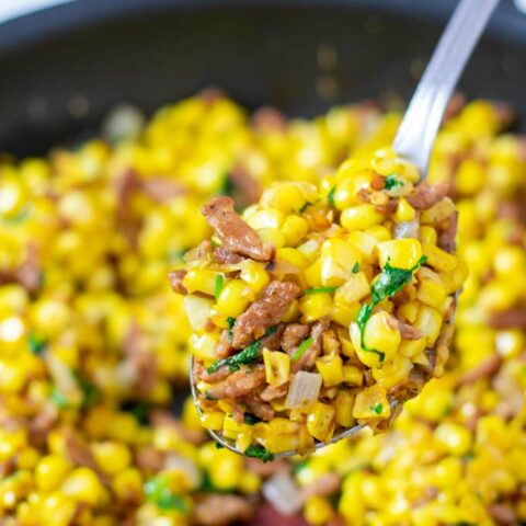 A large spoon of Fried Corn is lifted from the pan.