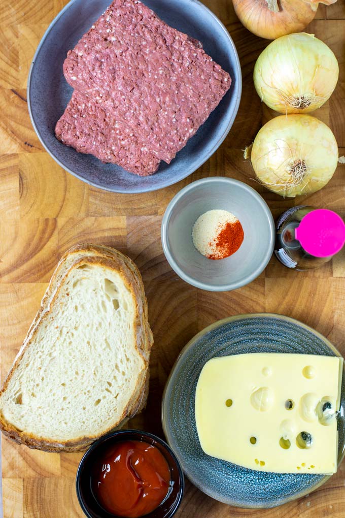 Ingredients needed to make Patty Melt are collected before cooking on a wooden board.