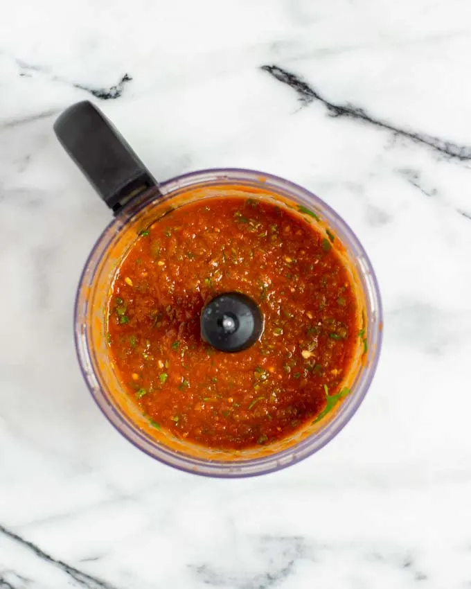 Top view on the bowl of a food processor with the processed salsa.