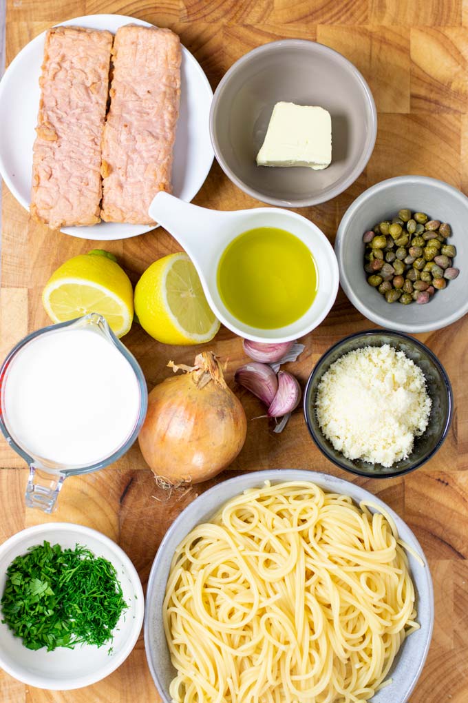 Ingredients for making the vegan Salmon Pasta are collected on a wooden board.