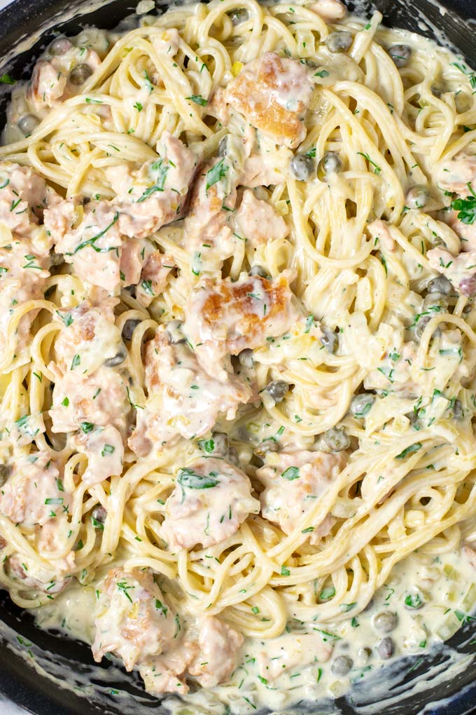 Closeup of the cream Salmon Pasta with salmon bits, fresh herbs, capers visible.