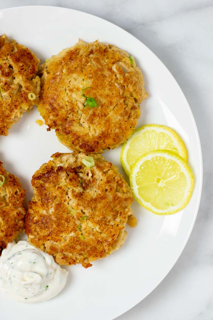 Closeup of two Tuna Patties with fresh herbs and lemon slices.