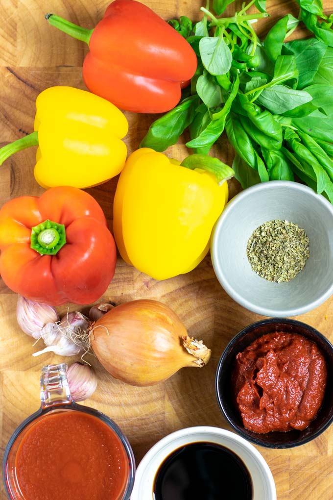Ingredients needed to make Peperonata are assembled on a wooden board.