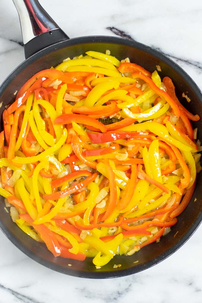 Sweet pepper and onions are fried in a pan with olive oil.