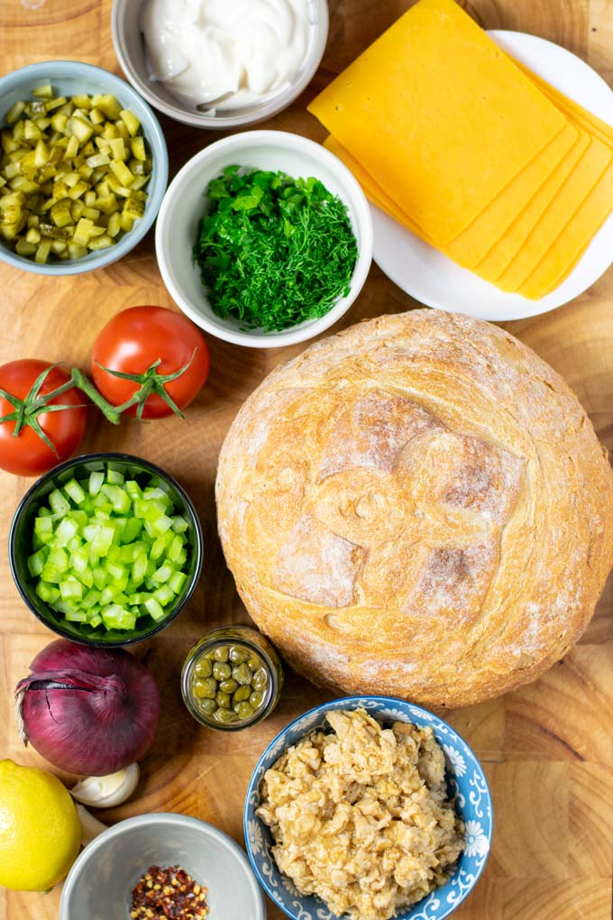 Ingredients needed to make vegan Tuna Melt are assembled on a wooden board.