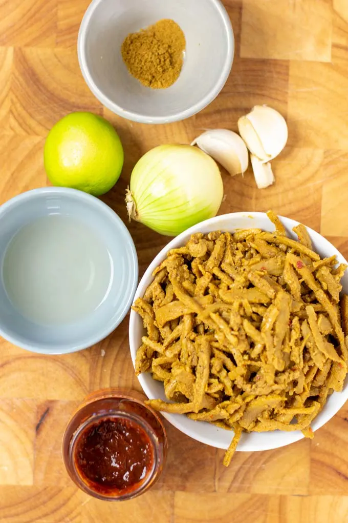 Ingredients needed for making Barbacoa are assembled on a wooden board.