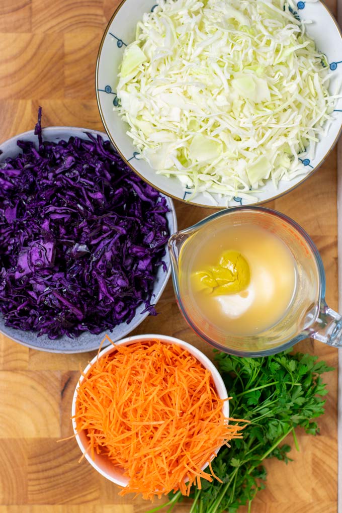 Ingredients needed for making Coleslaw are collected on a wooden board.