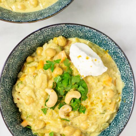 Closeup of a portion of the Mulligatawny Soup garnished with fresh herbs and yoghurt.