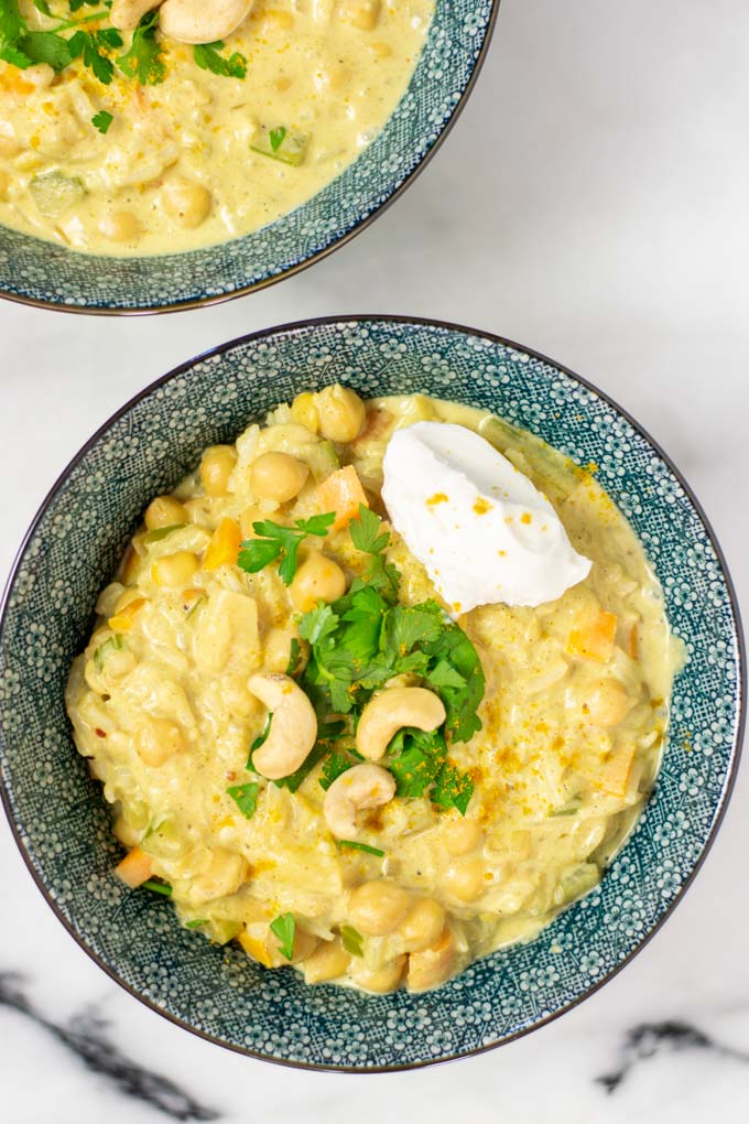 Closeup of a portion of the Mulligatawny Soup garnished with fresh herbs and yoghurt.