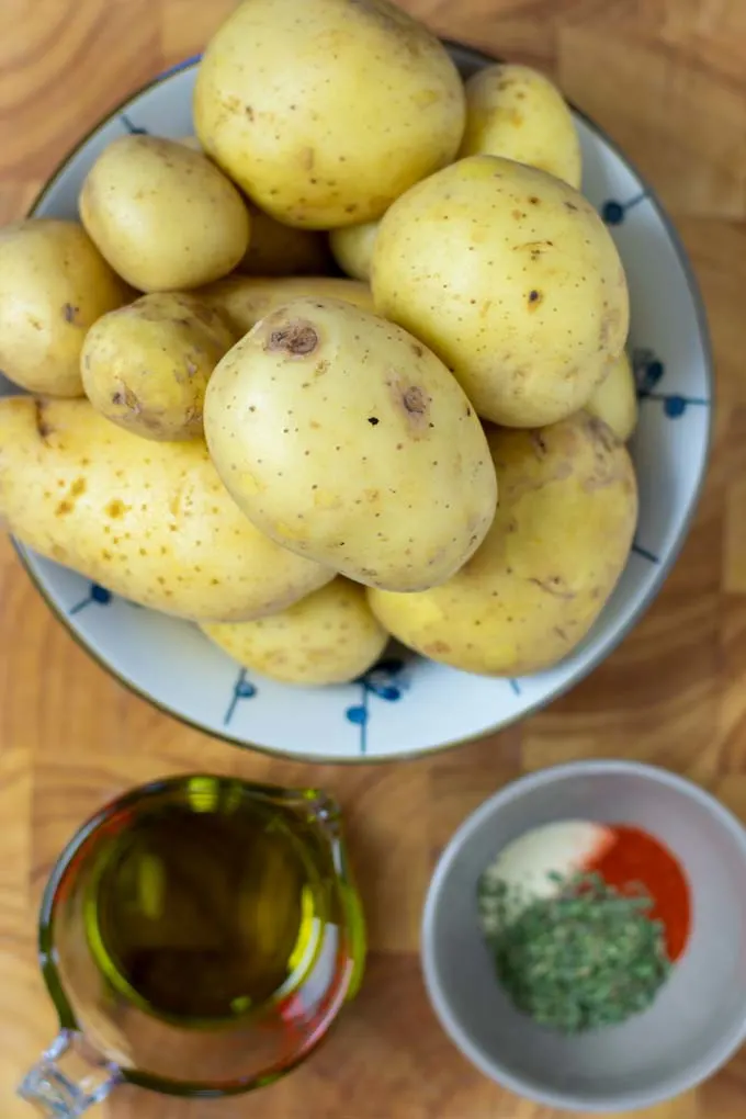 Ingredients needed for making Potato Wedges are collected on a wooden board.