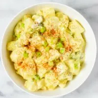 Top view of a serving bowl with the Southern Potato Salad, garnished with extra paprika powder.