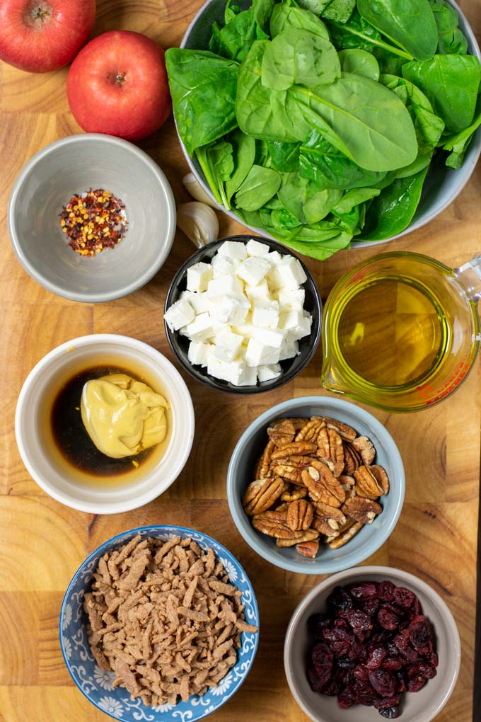 Ingredients needed to make Spinach Salad are collected on a wooden board.
