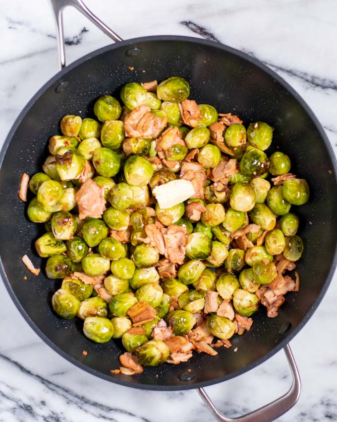 Mixed Bacon Brussels sprouts in a pan with a slice of butter. 