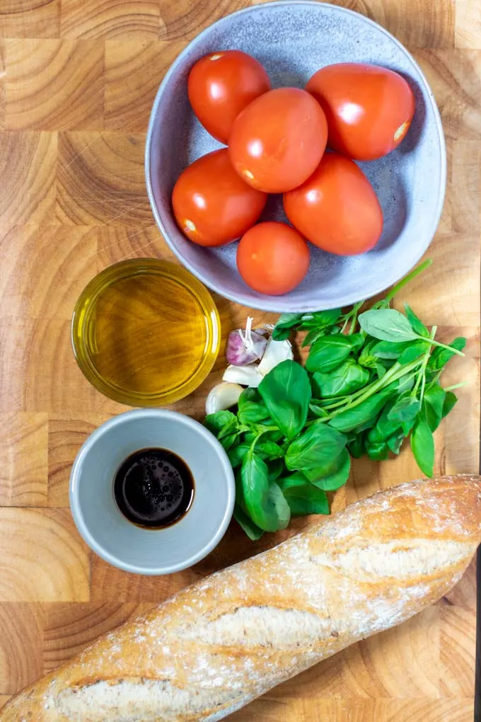 Ingredients needed for making Bruschetta are collected on a board.