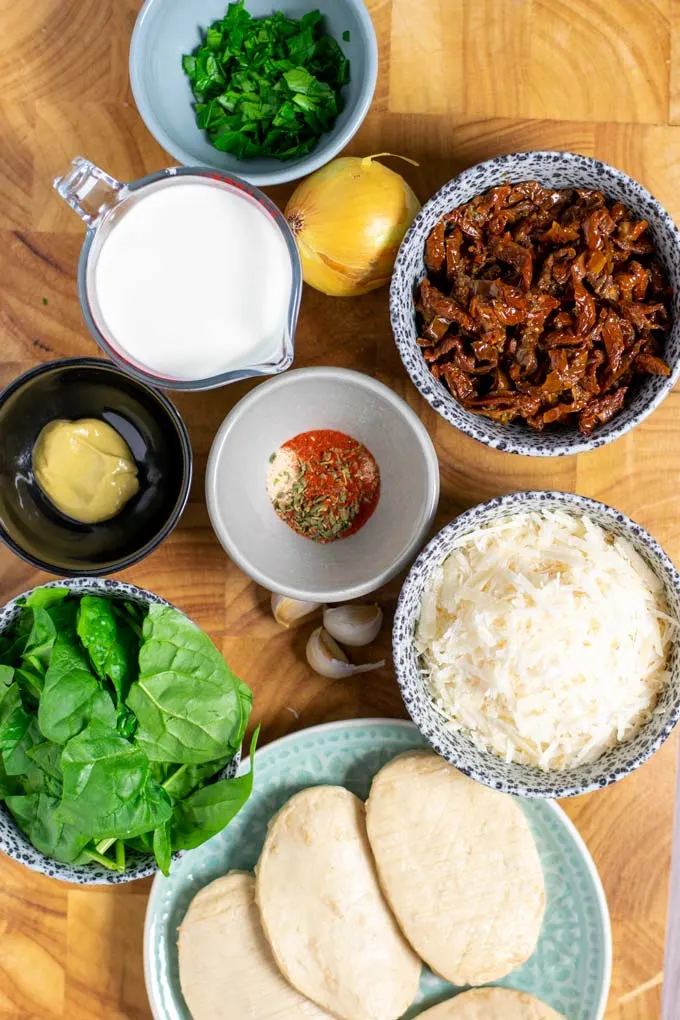 Ingredients needed to make Creamy Tuscan Chicken are collected on a board.